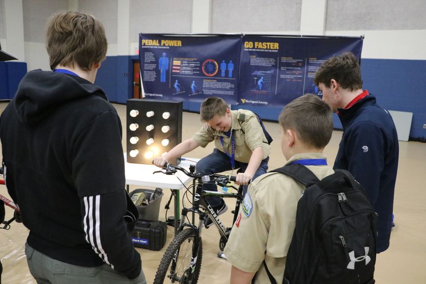 Boy scout powers light by riding a stationary bike. 